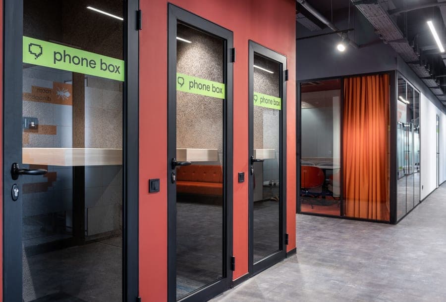 A single-person work booth with a desk and a glass door